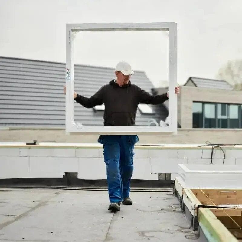 Vakman draagt een Skylux dakopstand over een plat dak voor een nieuwe dakopening