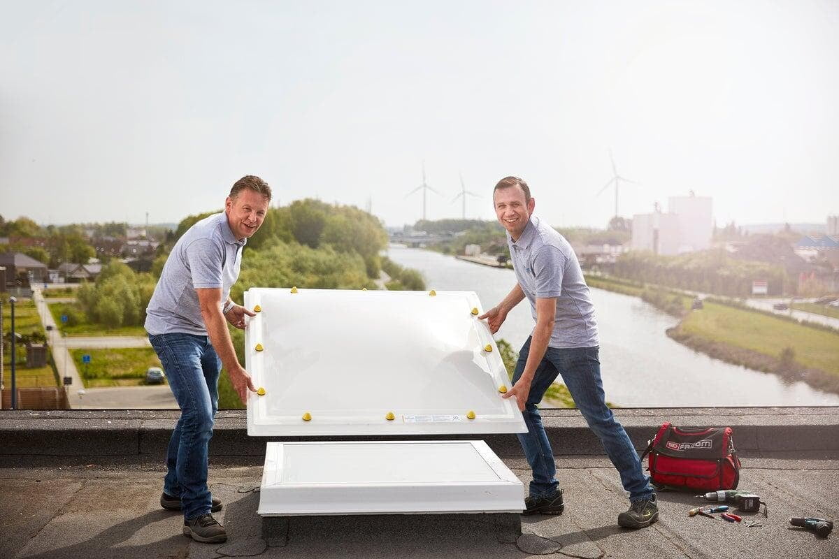 Twee vaklui plaatsen een nieuwe Skylux lichtkoepel op de bestaande opstand van een plat dak