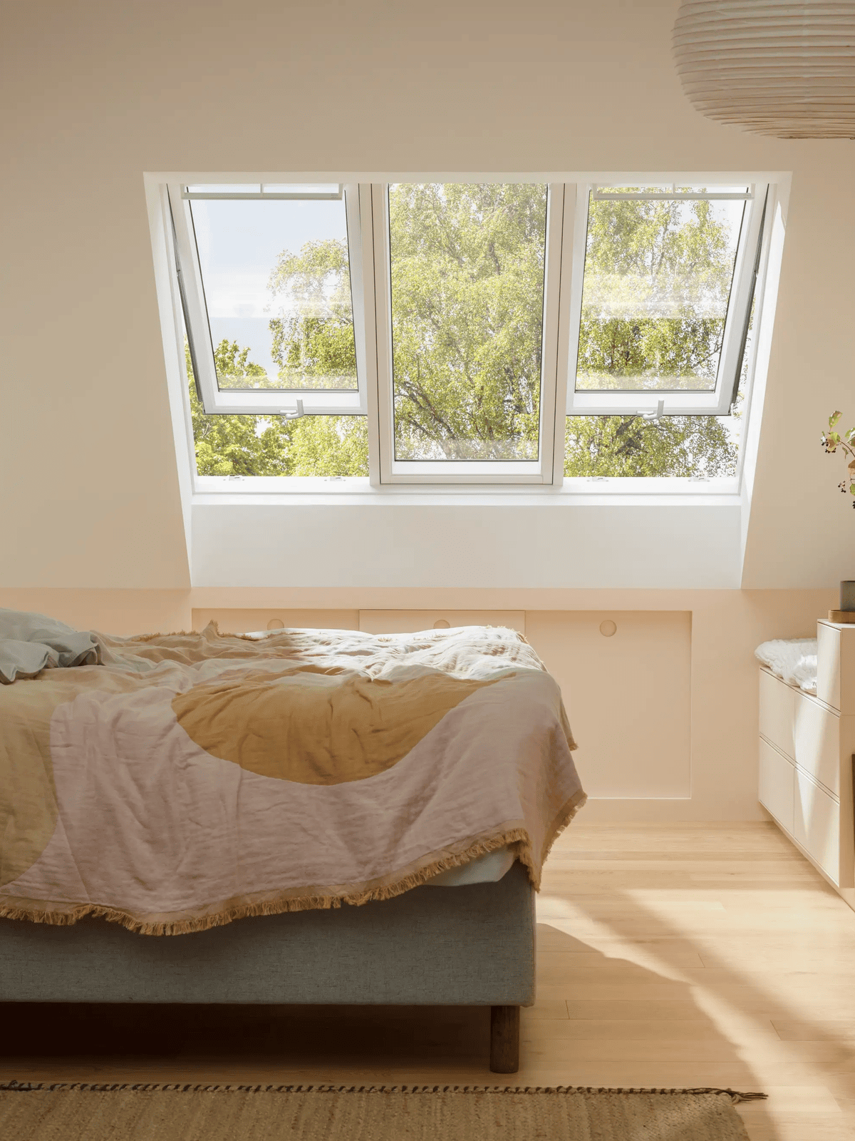 Slaapkamer onder het dak met drie VELUX dakvensters en uitzicht op groen