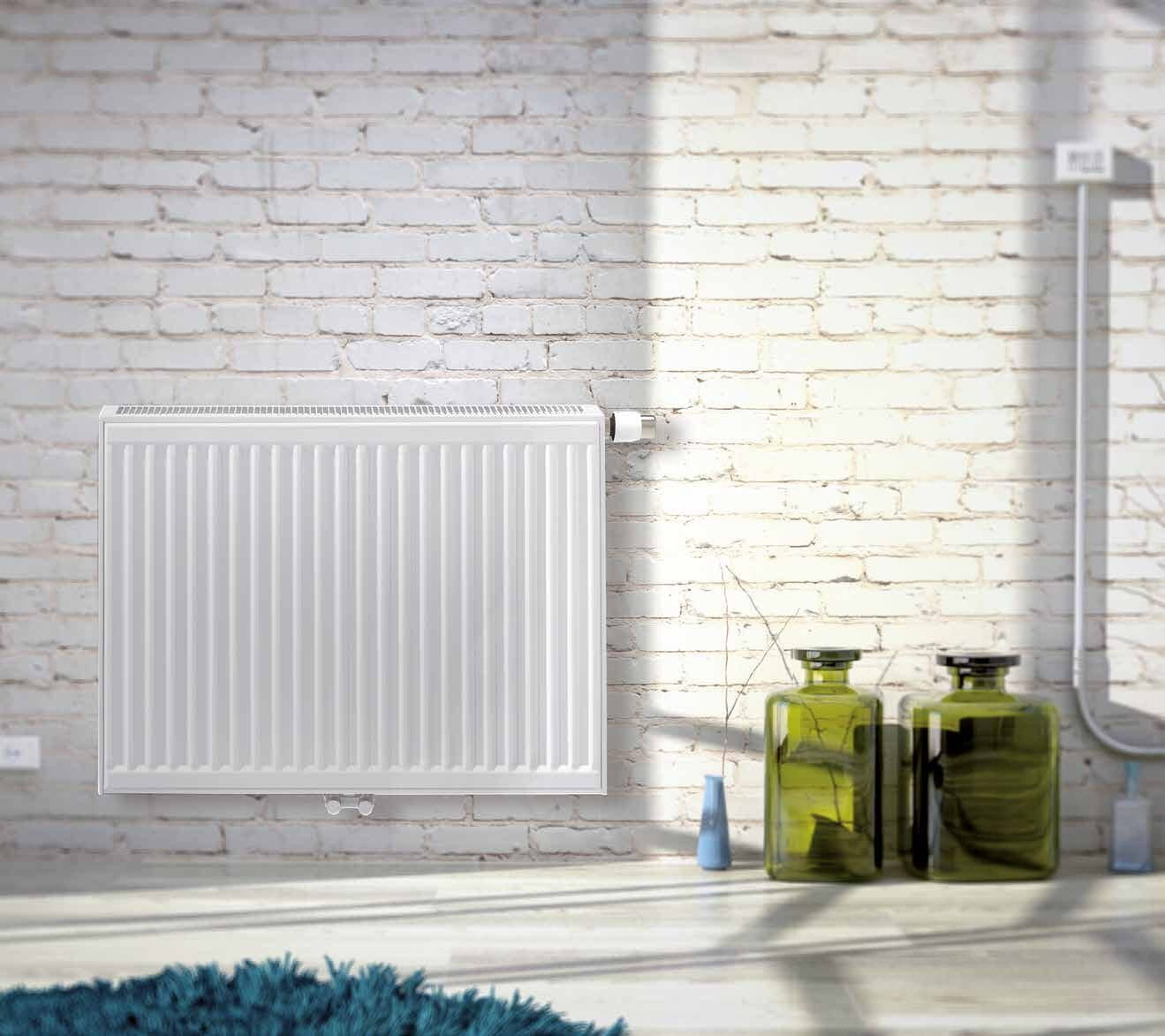 Witte paneelradiator tegen een witte bakstenen muur